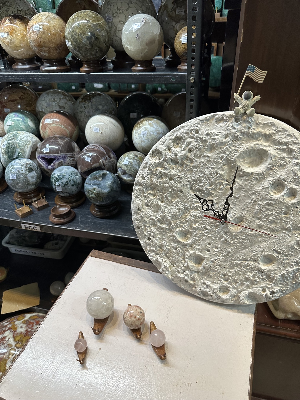 Crown Octopus gallery — moon-crater clock beside a shelf of gemstone spheres